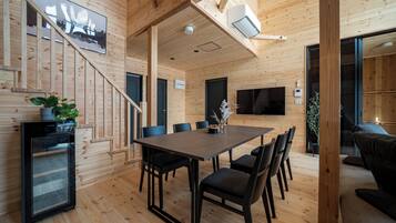 Un interior de madera con una mesa de comedor, sillas, un refrigerador y un sofá.