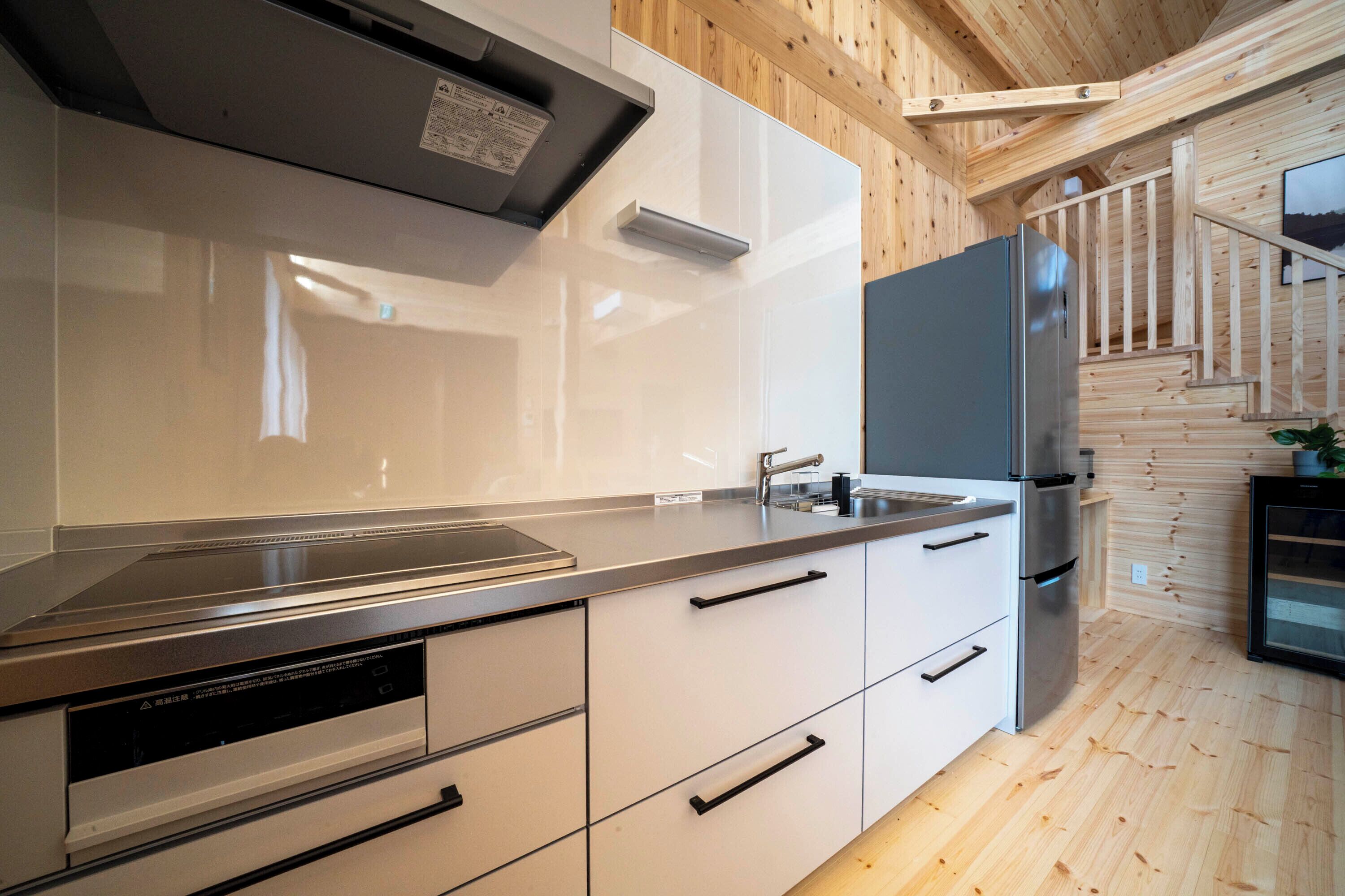 A modern kitchen with stainless steel appliances, white cabinetry, and a wooden interior.