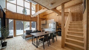 Een ruim houten interieur met een eethoek, keuken en een trap.