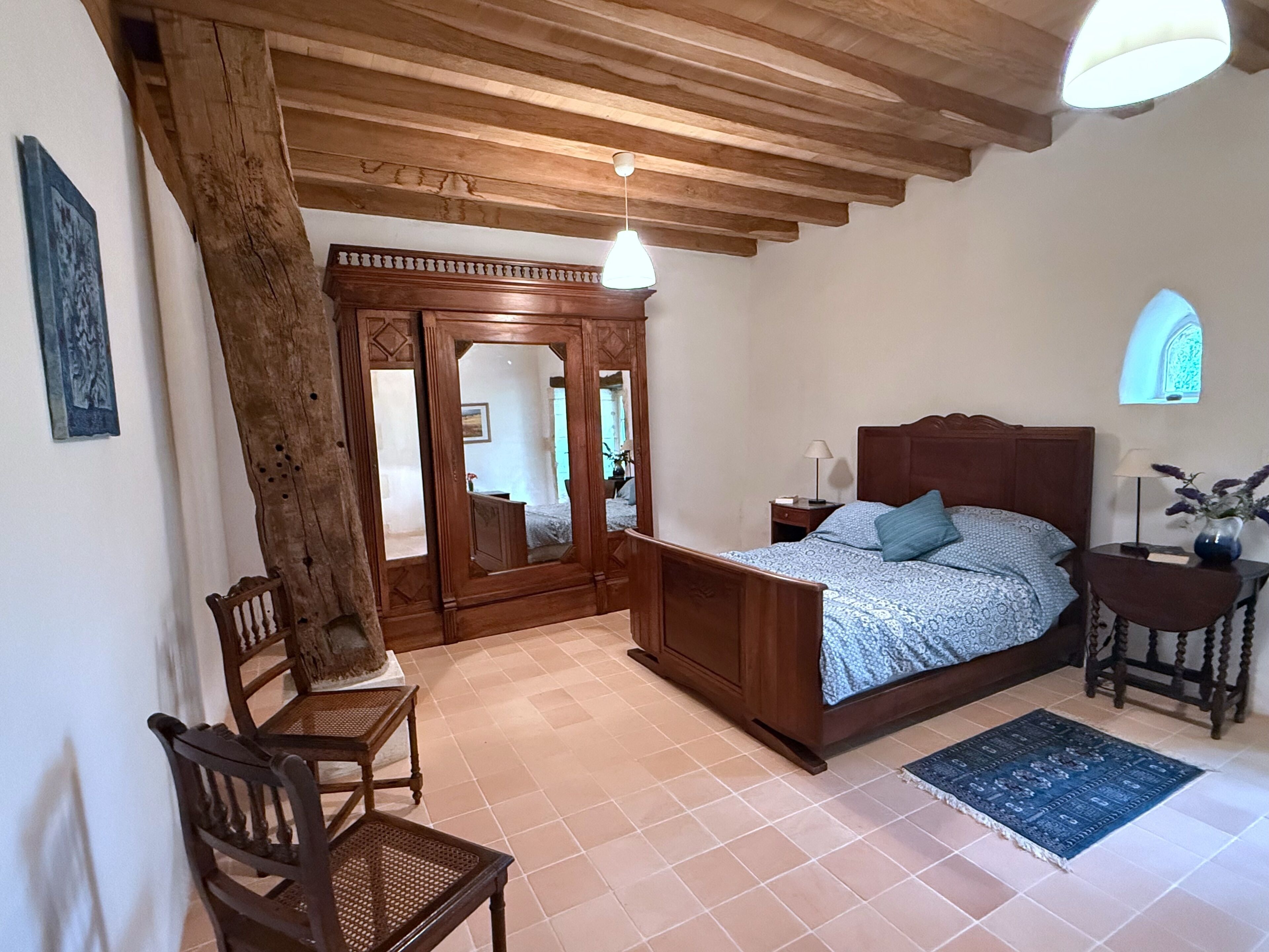 Ein Schlafzimmer mit einem hölzernen Bett, einem Sessel, einem Schreibtisch und einem Spiegel.