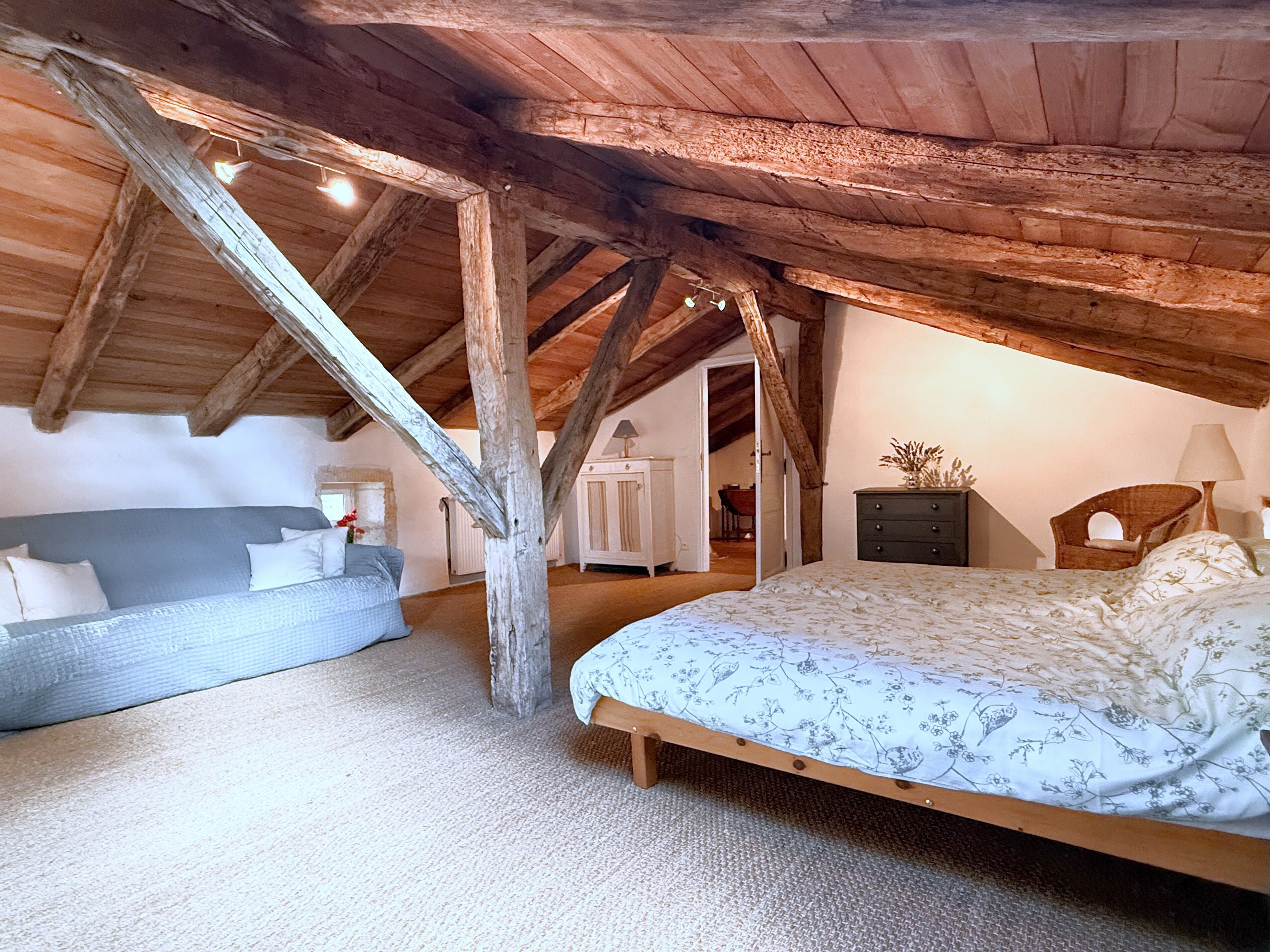 Una camera da letto con soffitto spiovente, un letto, una cassettiera e una sedia.