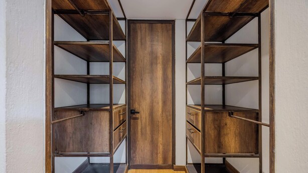 A walk-in closet with wooden shelving and a central door. - NOK Stylish 1BR Apartment in la Candelaria Bogota (Bogotá)