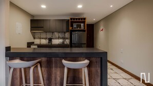 A modern kitchen with dark cabinetry, a central island with bar stools, a microwave, and a stainless steel refrigerator. - NOK Stylish 1BR Apartment in la Candelaria Bogota (Bogotá)