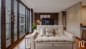 A modern living room with a sofa, a small side table, and a large window with a view of the outside. - NOK Stylish 1BR Apartment in la Candelaria Bogota (Bogotá)
