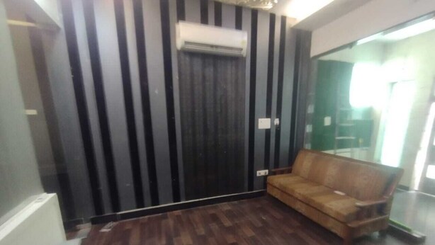 Ein Zimmer mit dunklem Holzboden, einem braunen Ledersofa und einer schwarz-weißen Streifenwand.