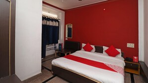 A hotel room with a bed, a nightstand, a desk, and a ceiling fan. - Townhouse GE Road Raipur Formerly Ratan (Raipur)