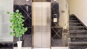 Un ascenseur doté d’un écran numérique, d’un téléphone et d’un escalier avec une rampe.