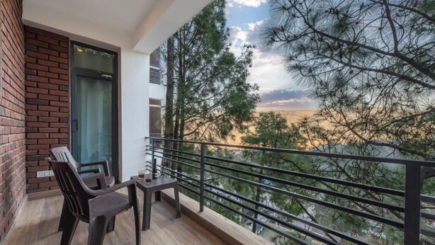 A balcony with a view of trees and a cloudy sky. - Kasauli Heights (Kasauli)