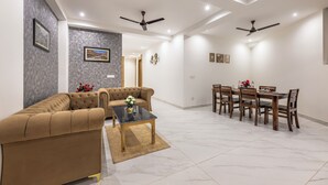 A modern living room with a sofa, a coffee table, and a dining area with a table and chairs. - Kasauli Heights (Kasauli)