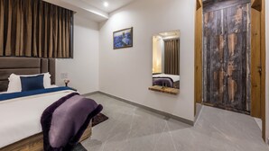 A modern bedroom with a large bed, a wooden wardrobe, a small bedside table, and a wall-mounted mirror. - Kasauli Heights (Kasauli)