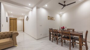 A dining area with a wooden table and chairs, a ceiling fan, and a sofa in a modern interior. - Kasauli Heights (Kasauli)