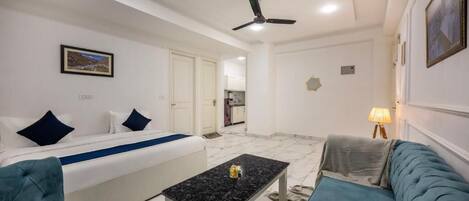 Une chambre d’hôtel avec un lit, un canapé, une petite table et un ventilateur de plafond.