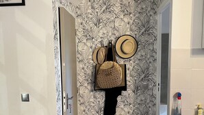Ein Flur mit strukturiertem Wandpapier, einem gerahmten Bild auf der linken Seite und einer Küchenzeile mit Spüle und Reinigungsmitteln auf der rechten Seite.