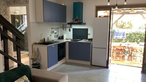 Eine moderne Küche mit blauen Schränken, einem Geschirrspüler und einem Kühlschrank. Durch eine offene Tür ist ein Essbereich mit Tisch und Stühlen zu sehen.