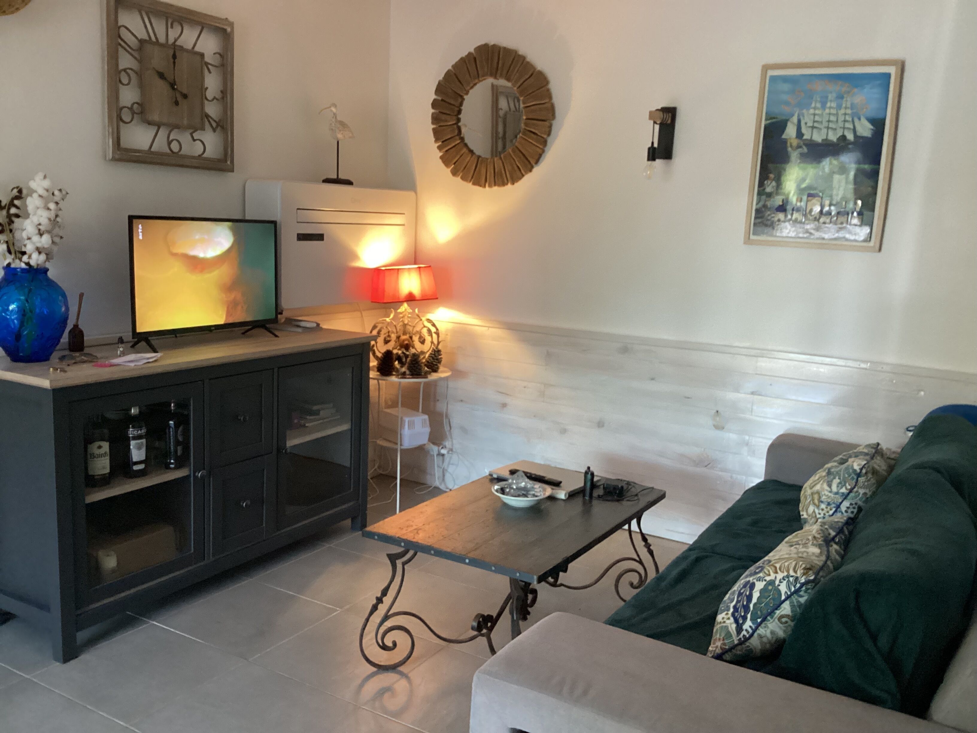 A living room with a sofa, a coffee table, a TV, a cabinet, a lamp, and a wall clock.