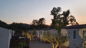 Een camping met stacaravans, een houten terras en een boom op de voorgrond.