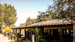 A rustic building with a tiled roof, surrounded by greenery and a parked car. - Cozy mobile home with terrace for 4 pers. (Sartène)