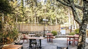 An outdoor patio with wooden tables and chairs, surrounded by a wooden fence and trees. - Cozy mobile home with terrace for 4 pers. (Sartène)