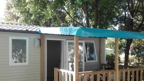Eine kleine, eingeschossige Holzhütte mit einer Veranda und einer Schiebetür.