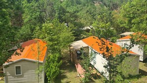 Un conjunto de cabañas con techos anaranjados ubicadas en un área boscosa con colinas al fondo.