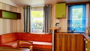 Una cocina compacta con una mesa y sillas de madera, un banco empotrado con cojines y una ventana con cortinas.