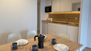 Een moderne keuken met witte kastjes, een houten aanrechtblad en een koffiezetapparaat op de tafel.