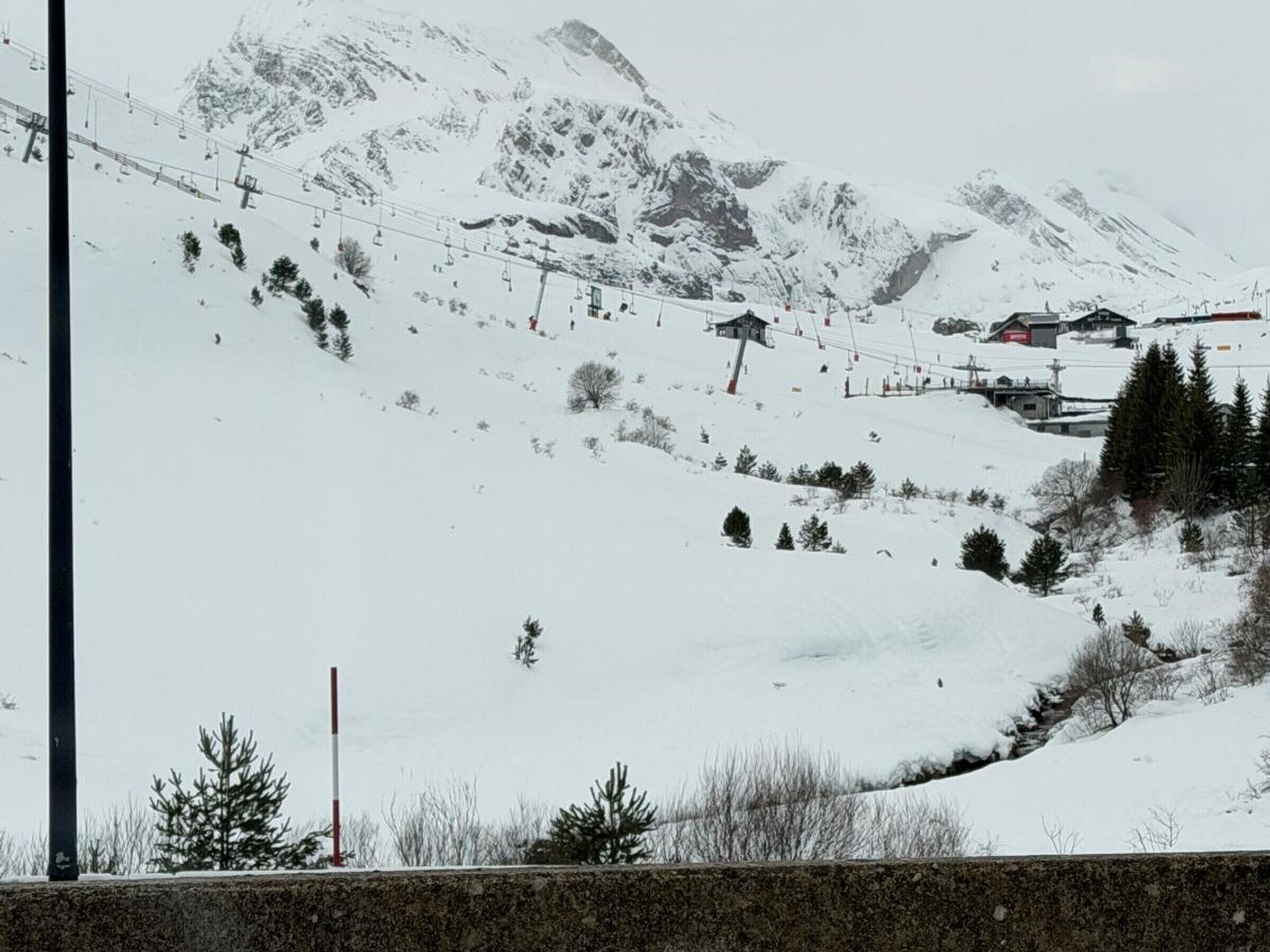 A snow-covered mountain with a ski lift and a few buildings in the background.