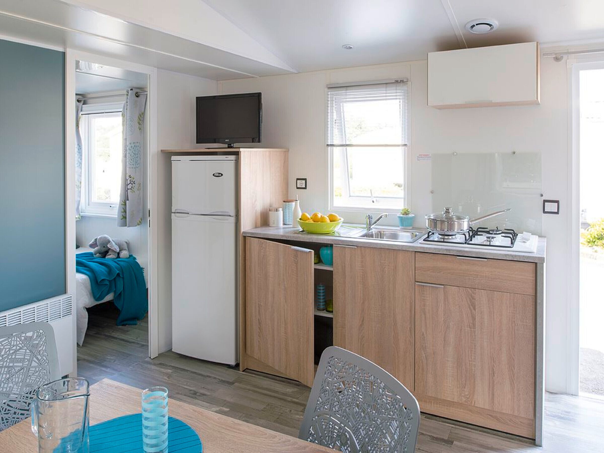 A compact kitchen with a refrigerator, a stove, and a sink. There is a dining area with a table and chairs.