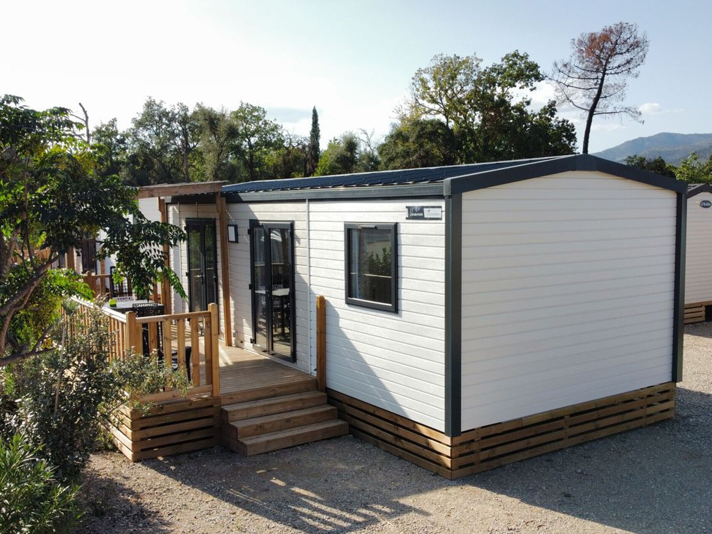 Une maison mobile de plain-pied avec un porche à l’avant, une petite terrasse et une fenêtre.