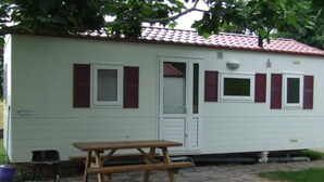 Une petite maison mobile d’un seul étage, avec un toit en tuiles et une terrasse en pierre.