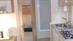 Une cuisine de taille réduite, équipée d’un évier, d’une cuisinière et de placards.