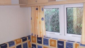 Une cuisine avec une fenêtre, un mur recouvert de carreaux et un rideau.