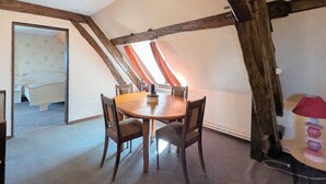 A dining area with a wooden table and chairs, a red lamp, and a view of a bedroom through an open door. - Countryside home near Châteauroux, family-friendly (Arthon)