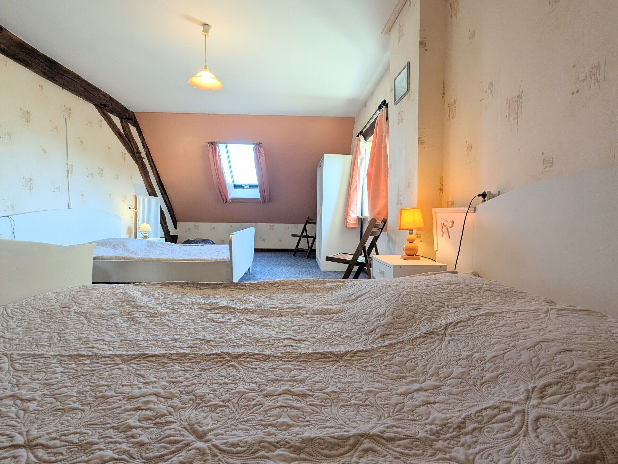 A room with a large bed, a desk, a chair, a window, and a radiator.