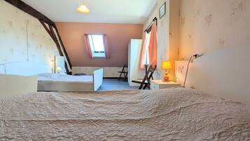 A room with a large bed, a desk, a chair, a window, and a radiator.