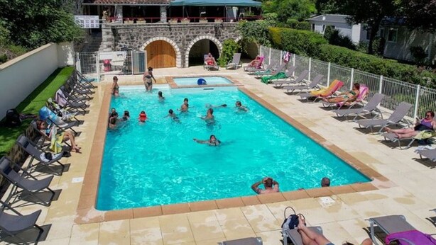 A swimming pool with multiple lanes, surrounded by lounge chairs and a stone building with arches. - Spacious mobile home for 8 with terrace (Lavilledieu)