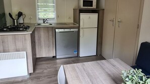 A compact kitchen with a stove, sink, microwave, and refrigerator. - Mobile home 27sqm, 6 pers, 3 bed, terrace (Espira-de-Conflent)