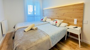 A bedroom with a wooden headboard, two beds, a bedside table with a remote, and a window with sheer curtains. - Modern Studio in Candanchú, 4 ppl, 2 beds (Aisa-Candanchú)