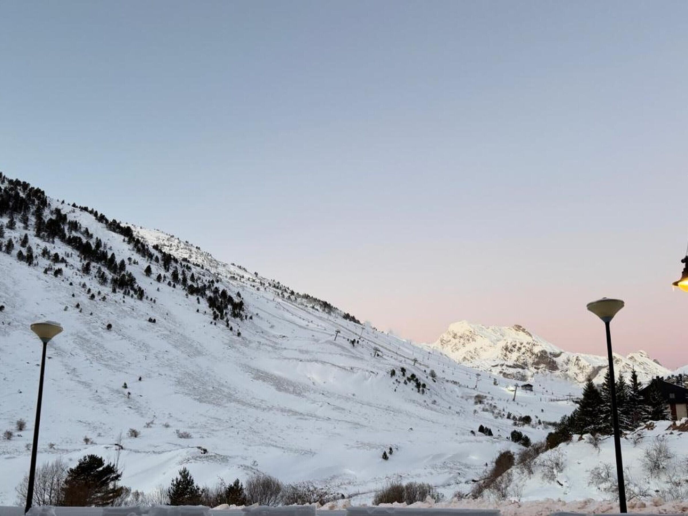 A snowy mountain landscape with street lamps and a clear sky.