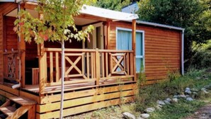 A wooden cabin with a porch, a small deck, and a window. - Comfortable Mobile Home for 4 pers. with Terrace (Espira-de-Conflent)