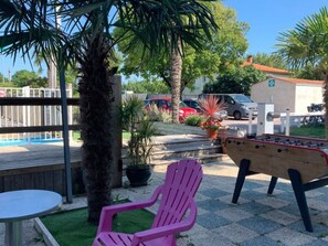 A poolside area with a foosball table, a pink chair, and a small table. - Mobile Home with Terrace for 4 People (Arvert)