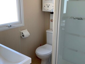 Un baño con inodoro, un dispensador de toallas de papel y una ventana.