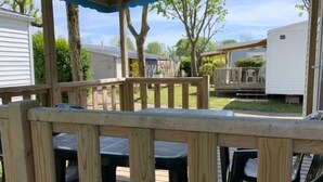 Una terrazza esterna riparata con ringhiere in legno e sedie in plastica nera.