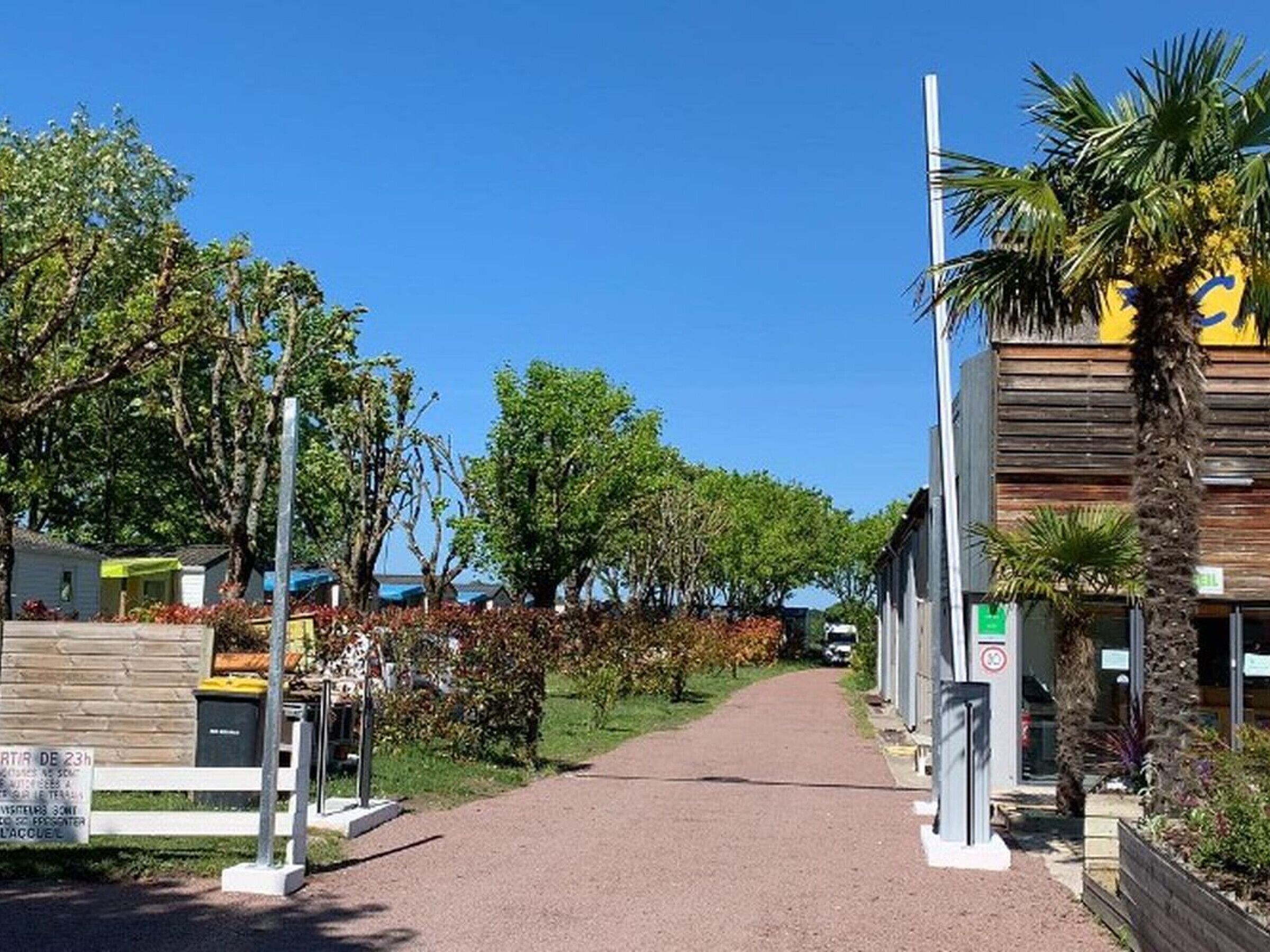Un camí que condueix a un edifici amb un senyal que indica una zona de servei de 23 hores.