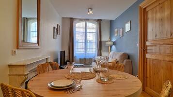 A dining area with a round wooden table set for four, surrounded by wicker chairs.