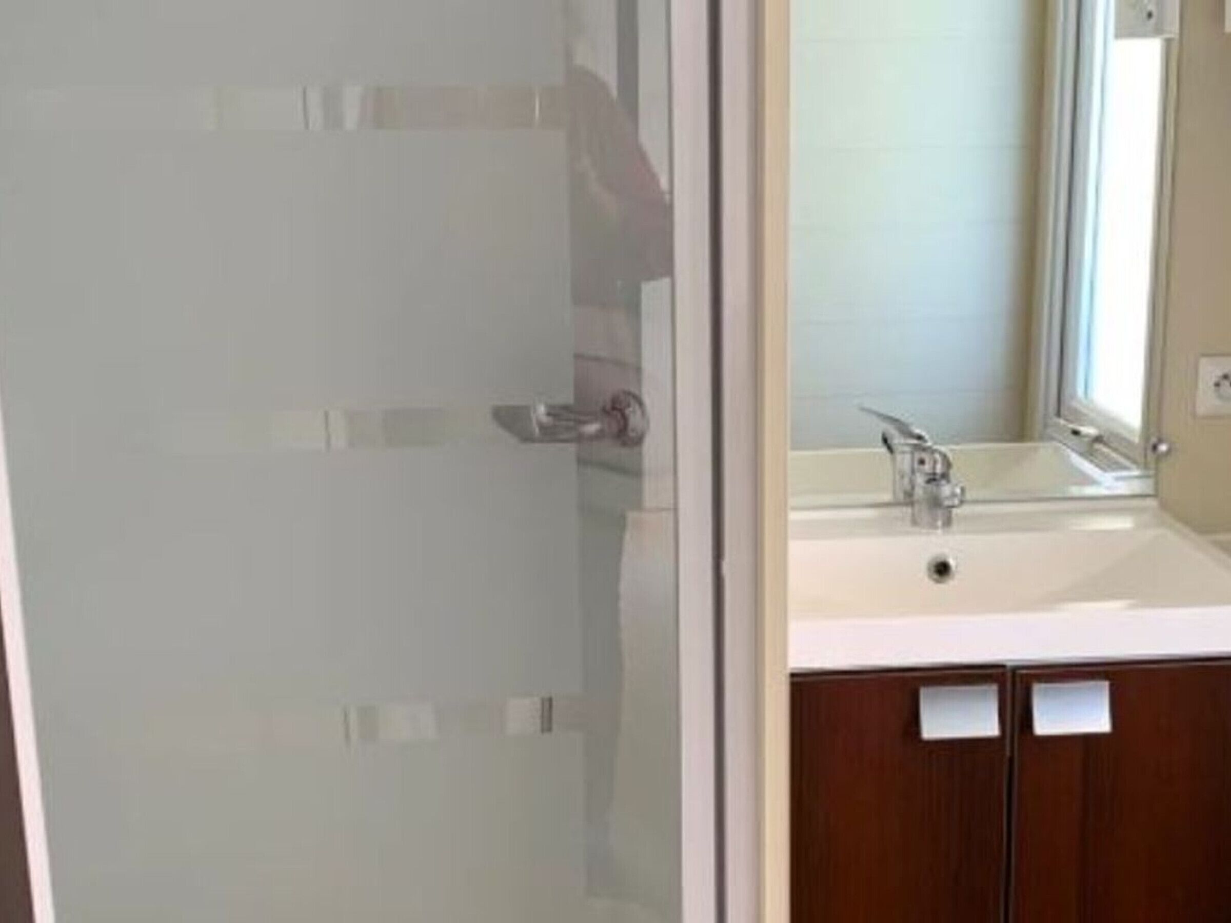 Un bagno con porta in vetro, lavandino e mobili in legno.