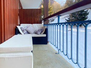 A balcony with a white sofa and cushions, a blue railing, and a view of a snowy landscape. - Arc 1800 - Apartment 6 pers, 74m², WIFI (Les Arcs 1800)