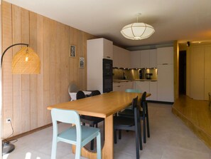A modern kitchen with wooden panel walls, a dining table with chairs, and a pendant light. - Arc 1800 - Apartment 6 pers, 74m², WIFI (Les Arcs 1800)