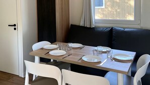 A dining area with a wooden table set for four, white chairs, and a black sofa.