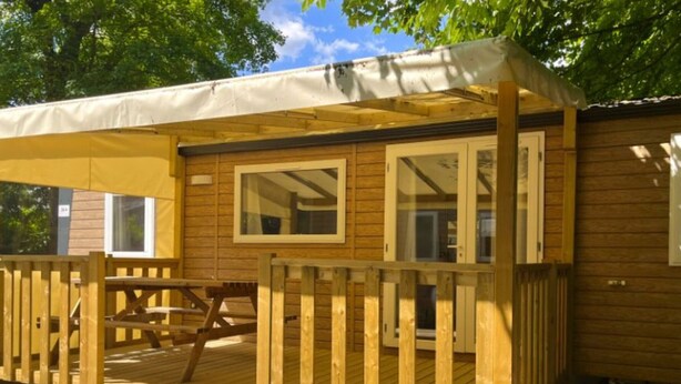 A wooden cabin with a covered deck and a picnic table.